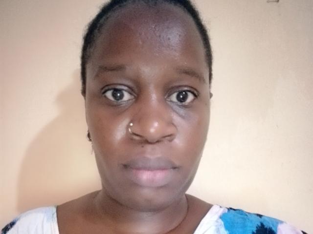 SexyBrexy has dark skin, a nose ring, and a neutral expression. She's wearing a floral top with blue, white, and black patterns. Her eyes are slightly open.
