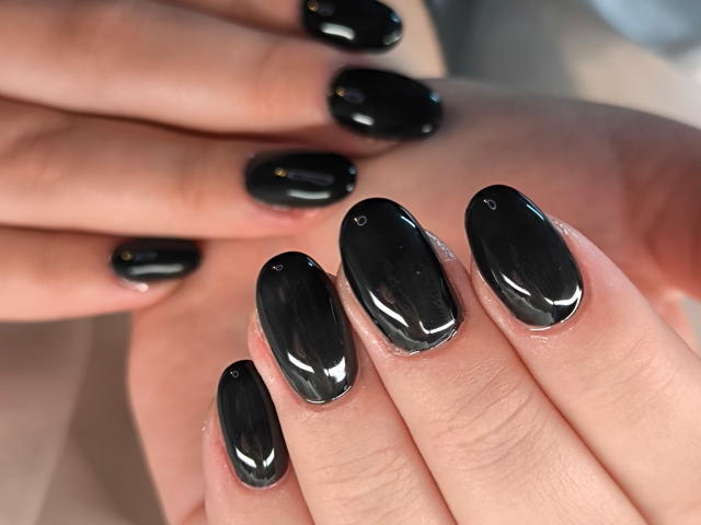 ElvinnaLaFrancaise's shiny black nails are glossy and smooth, with a slight reflection on each polished oval tip, showing off her well-manicured hands.