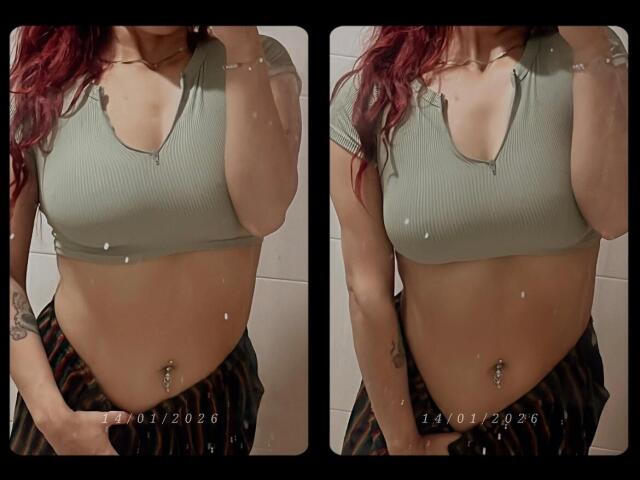 AlexaFoster with red hair, green ribbed crop top, showing her tits and belly button piercing, wearing striped pants, left hand in pocket, two side-by-side mirror selfies.