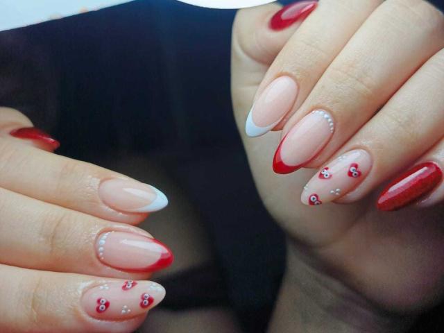 LissyCarter's nails are glossy and sexy with a French tip style, featuring red tips, pink base, and cute red rhinstones on the ring fingers. Her hands are stylish.