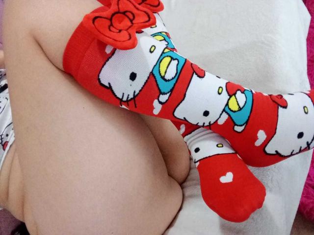 SamanthaCollen's legs with red and white Hello Kitty socks, featuring cute faces and red hearts, sitting with her ass slightly exposed on a white surface.