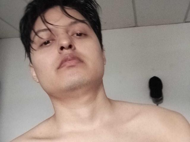 KevinCharles, shirtless with wet black hair, slightly flushed skin, and a neutral expression, has a small patch of stubble on his chin. A black hairbrush is in the background.