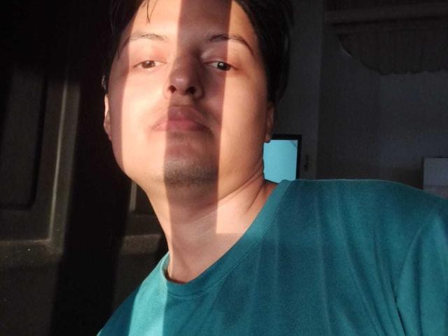 KevinCharles has a medium skin tone, short black hair, and is wearing a teal shirt. A shadow is partially over his face. He has a slight beard and mustache.