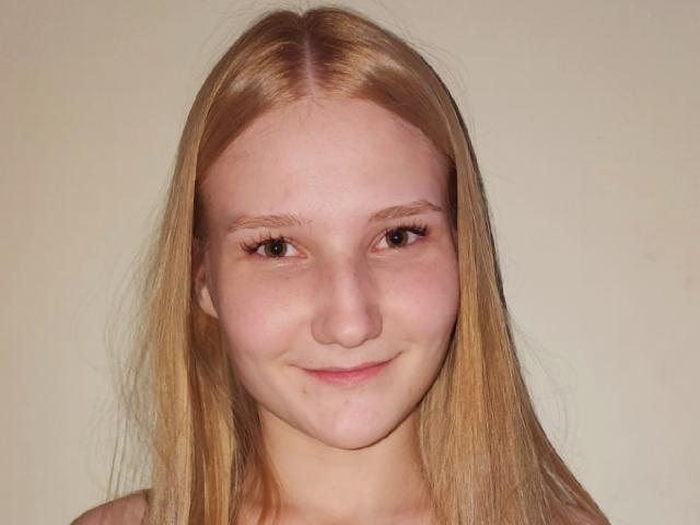 VanessaNorris has straight blonde hair, light skin, brown eyes, and a small smile with slightly parted pink lips. Her ass is not visible.
