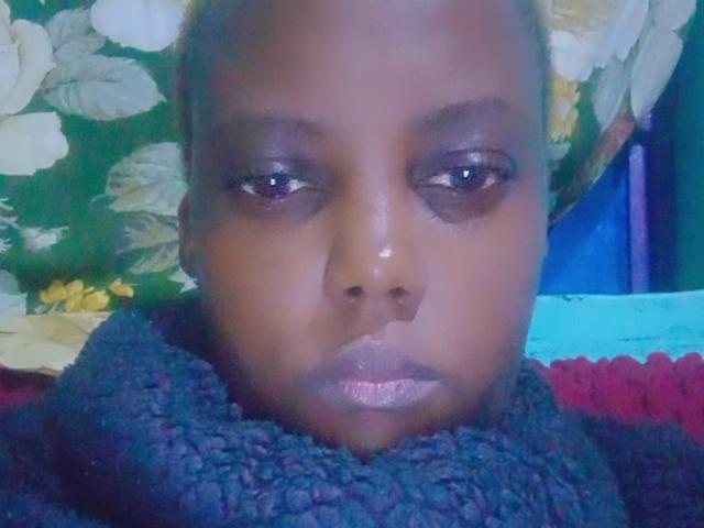 Starlesty's face, dark skin, shiny lips, half-closed eyes with dark eyelids, wearing a thick, textured black scarf, looking straight at the camera with a neutral expression.