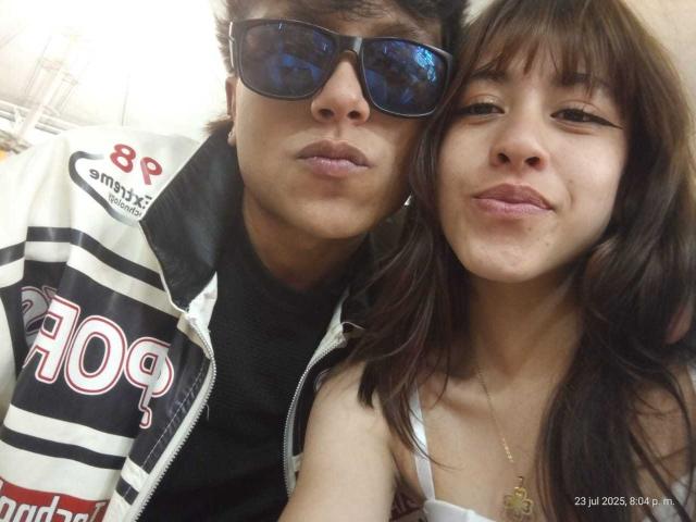 FeviceFabinLm in a hockey jacket with "409" and black sunglasses, next to a brunette with pouty lips and a necklace, both smiling. Date stamp in bottom right.