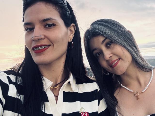 DakottaScarlett with black hair, red lipstick, nose ring, and striped shirt, standing next to DakottaScarlett with gray hair, red lipstick, pearl necklace, and white top.