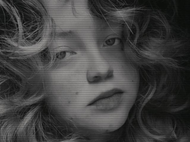 ChubbyLeahPearl's face is in a black-and-white shot with her curly, messy hair, slightly parted lips, and a few small moles. Her eyes are looking off to the side.