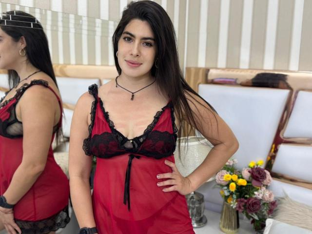 JasminSwit stands in red and black lace lingerie, showing her tits and small ass in a mirror reflection. She has long dark hair, a necklace, and a smile.