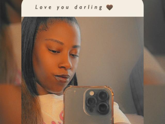 Ebhony's reflection shows her with brown skin, straight black hair, and dark lipstick, holding a phone with a camera in front of her, in a selfie. Her tits are small.