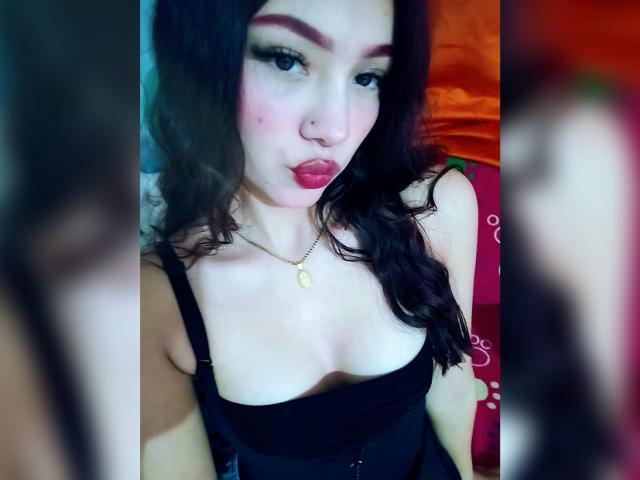 ValerieCasanova has puffy red lips, dark wavy hair, black strap dress, showing small tits, nose ring, and gold necklace, with a pouty expression. Blurred mirror reflections on sides.