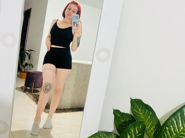 Valeriaaf with red hair, black sports bra, black shorts, white socks, tattoo on left thigh, taking a mirror selfie, showing her ass and tits.