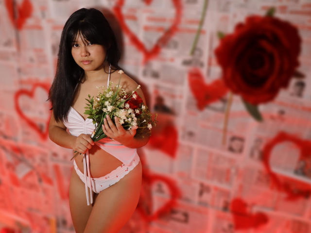 Mei69 met zwart haar, witte bikini, een boeket vasthoudend, staand, kleine borsten zichtbaar, witte onderbroek, een boeket vasthoudend, rode en witte achtergrond, rozen als decoratie, zachte belichting..