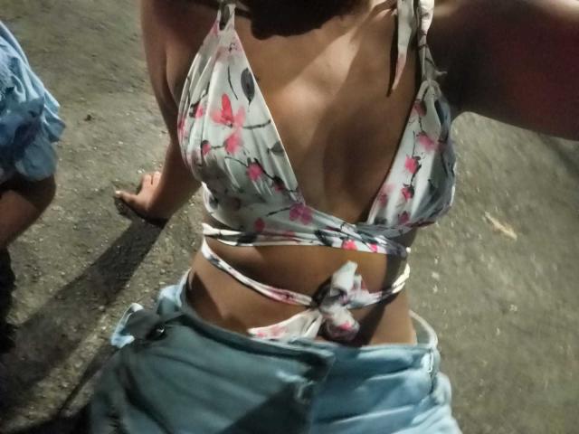 AmelieRose's tits in a white floral bikini top, showing cleavage, with tied strings, and blue jeans partially pulled down, revealing her bare midriff and tan skin.