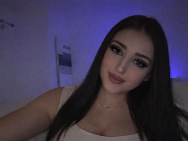 MiaHaveFun has long dark brown hair, big green eyes, full pink lips, and is wearing a white top with a delicate necklace, looking cute and sexy.