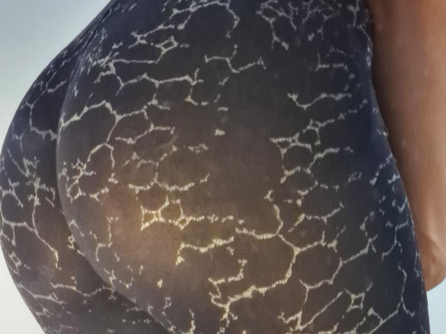 NaylaGrey's ass in a tight, black, lace-patterned fabric showing her butt's shape and texture. The lace is white, creating a contrasting, web-like design.