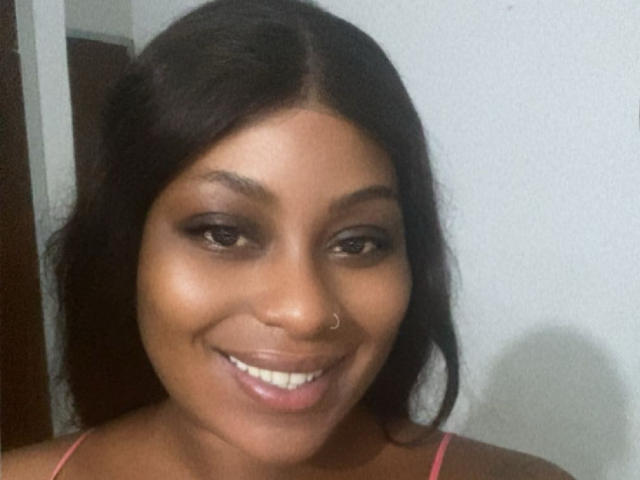 Solene69 has dark brown skin, a cute nose ring, and is smiling with her pink tank top. She has black hair and brown eyes. Her tits are not visible.