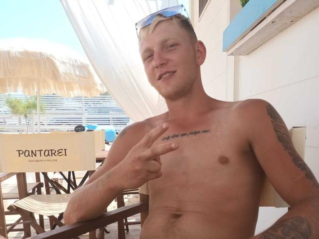 Shirtless Argantely69 with tattoos, making a peace sign, has a slight smile, blue-tinted sunglasses on head, and a "Pontorei" sign in the background.
