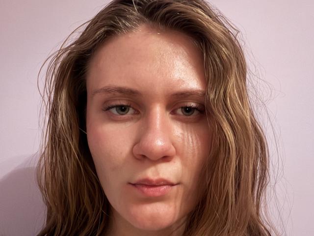 EricDekenipp has wet, messy brown hair, green eyes, and a slightly pouty, expressionless face with light skin, showing a few small freckles and a slight sheen on the nose.