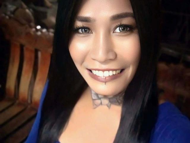 MisstessGalaxia-hot has black hair, blue eyes, a cute smile, and a tattoo under her chin. She's wearing a blue top and has a small drop of saliva on her teeth.