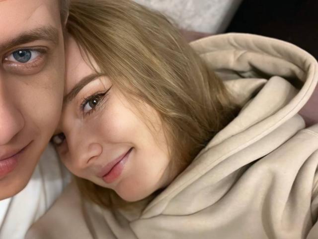 ShawtyMia's face is nestled under ShawtyJack's chin, both with blue eyes and blonde hair, ShawtyMia smiling, ShawtyJack's nose partially visible, ShawtyMia in a beige hoodie.