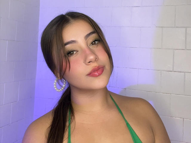 LorensDouce has brown hair in a ponytail, green halter top, pink lipstick, hoop earrings, and a nose ring, with a cute face and slightly upturned nose.