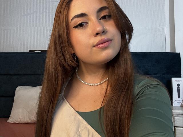 VicluX ha i capelli castani, gli occhi verdi e una collana di perle, indossa una maglietta verde e bianca, con un sorriso appena accennato, mentre guarda la fotocamera. Ha il seno piccolo..