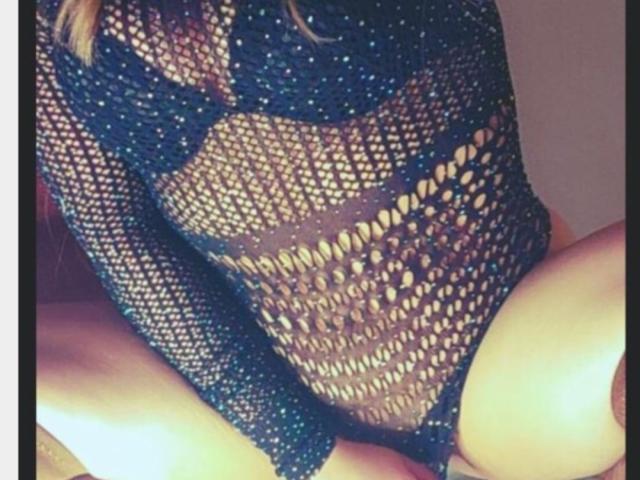 SweetyNiyaaOne wearing a dark blue, glittery fishnet bodysuit that exposes her tits and pussy, with her thighs visible and knees slightly apart.