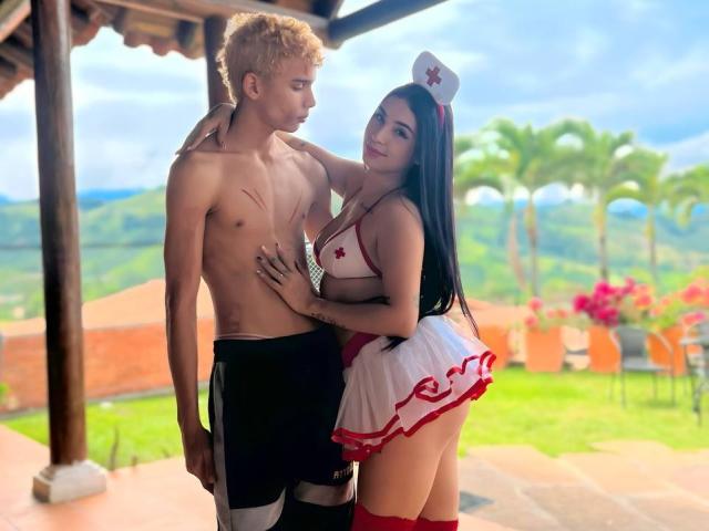 ArdienteCouple with blonde, curly-haired dude, shirtless, in black shorts, and ArdienteCouple with black hair, red cross nurse outfit, white hat, red skirt, white top, touching his chest.