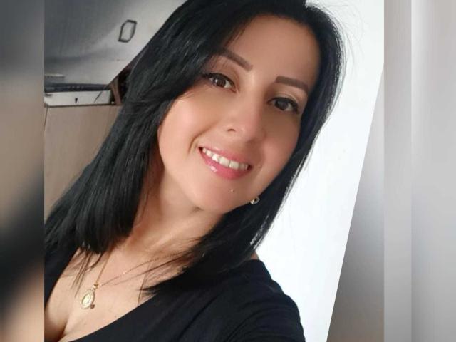 Briananice has black hair, brown eyes, and a cute smile with pink lipstick. She's wearing a black top and a gold necklace with a small pendant.