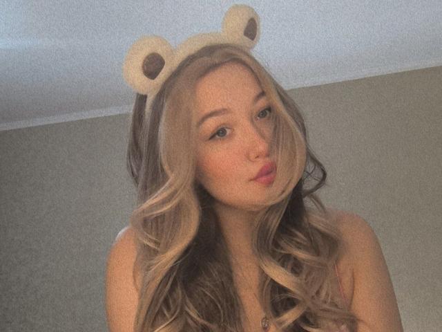 CloraFlippin with long, wavy blonde hair, pouty pink lips, and bear ears headband, looking cute and sexy, showing her bare shoulders.