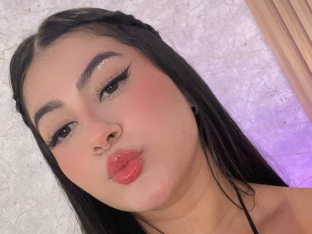 AlanaaWalker has pouty red lips, thick black eyebrows, long eyelashes, and glossy brown eyes. She's pouting her plump lips with a slight blush on her fair skin.