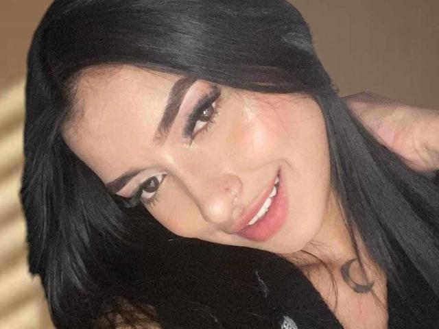 IrisBeaumont with black hair, smiling, brown eyes, full lips, slightly glossy skin, a nose ring, and a crescent tattoo on her neck, looking cute and sexy.