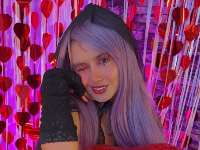 YukkyKuran with purple hair, black lace glove, and hood, winking with a smile, wearing red and black, showing off a cute face and a sexy look.