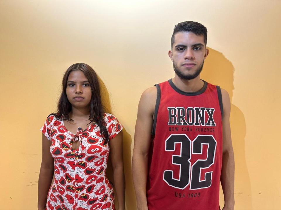 BigSubmission, dark-skinned girl with medium breasts, wearing red floral dress, stands next to BigSubmission, dark-skinned guy with short beard, wearing red basketball jersey, number 32.