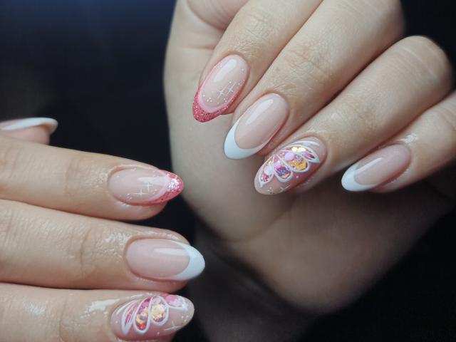 LissyCarter's nails are a glossy pink with white tips, glitter on the tips, and colorful floral designs on the nails. Her hands are shown in a close-up.