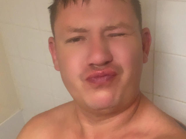 RemyBartss has a chubby face, slightly wet skin, and is making a silly pouty face with one eye closed. He's shirtless with short brown hair.