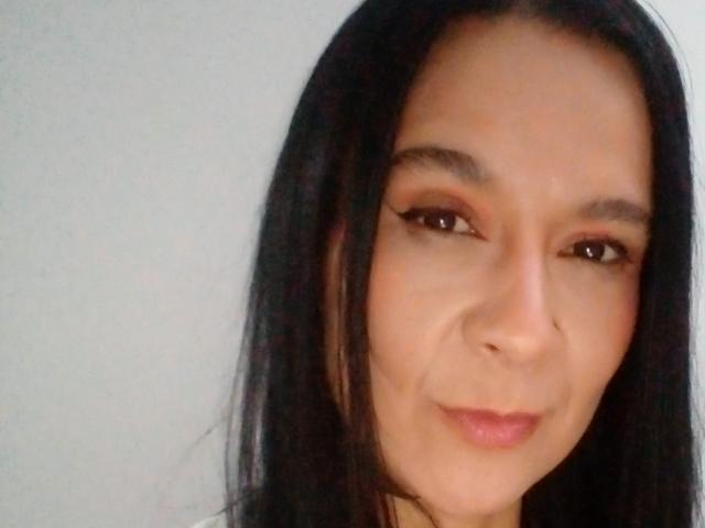 AileenRamirezW has medium brown skin, long black hair, brown eyes with winged eyeliner, and a slight smile. Her nose is small and she has full pink lips.