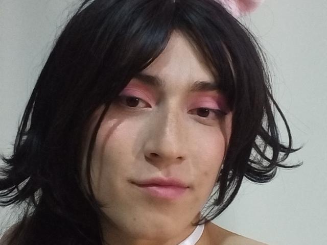 EllieCherry with black wavy hair, pink eyelid makeup, and pink bunny ears, has a cute face and subtle smile, showing a slight freckle on her right cheek.