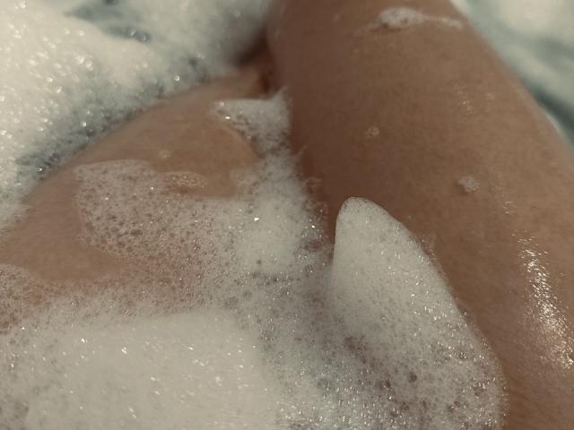 La vulve mouillée et savonneuse de Diantrisy, recouverte de bulles sur la partie inférieure de son corps et sur les cuisses, dans un plan rapproché et détaillé..