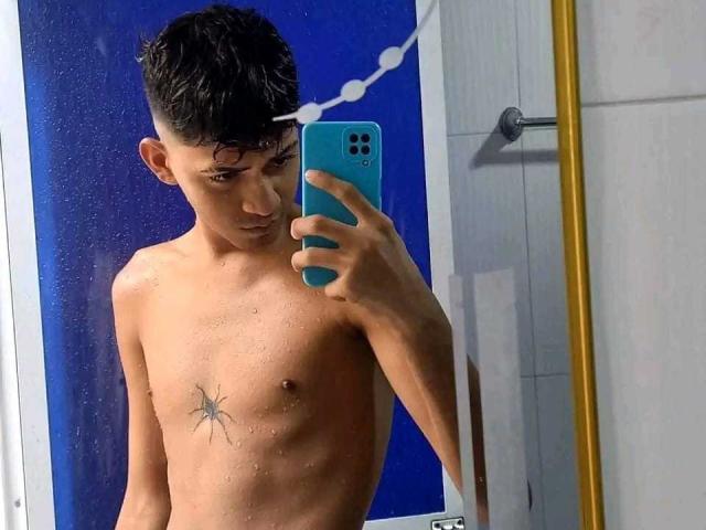 Shirtless BabeBluexy with wet skin, short dark hair, small star tattoo on right side of chest, holding blue phone in mirror selfie, blue background, yellow mirror frame.