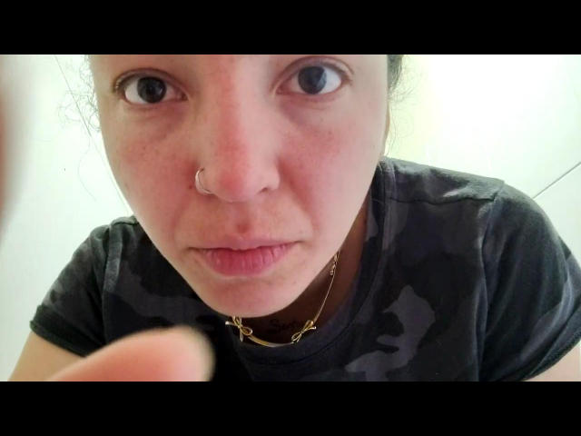 WildSelena69 has a nose ring, freckles, and is wearing a camouflage shirt with a gold necklace, looking up with wide eyes and a slight pout, holding a finger.