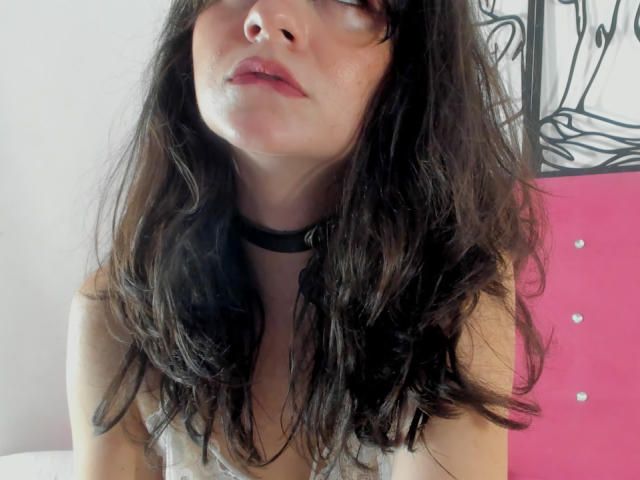 KariCarter has wavy black hair, a black choker, and slightly parted pink lips. She's wearing a white sleeveless top, and her nose is visible. Her eyes are looking upward.