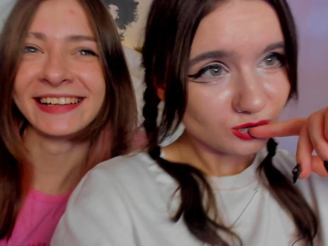MaoandLulu with brown hair in braids, white shirt, red lipstick, and nose ring, biting finger, next to MaoandLulu with pink shirt, smiling. Both have fair skin.