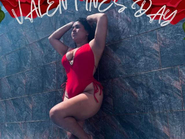 LianaAndAsaff is a curvy woman with large tits and a thick ass, wearing a red one-piece swimsuit, leaning against a dark tiled wall with arms above her head.
