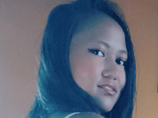 KiasimVioletta has dark, straight hair and a cute smile with black eyeliner. She's looking over her shoulder, showing a small nose and shiny lips. Her skin is light.