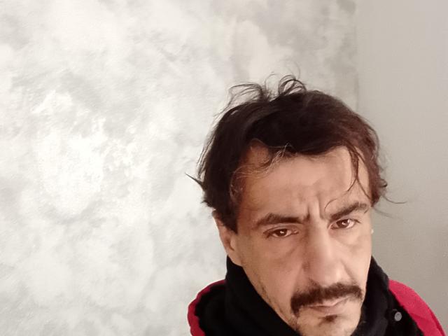 Dragone69 has a wrinkled face, dark messy hair, and a thick mustache. He's wearing a red and black shirt. His expression is slightly annoyed.