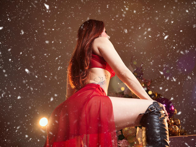 RoseNichols avec une robe rouge transparente, des bottes noires, de longs cheveux bruns, un tatouage sur le côté, de la neige qui tombe, une jambe levée, fesses visibles, vue de dos, lumière chaude, sexy, attirante..