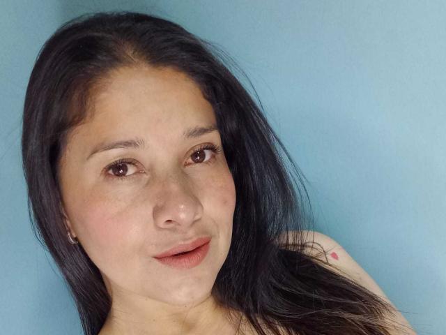 AlanaSteel has long black hair, brown eyes, and a slight smile. She has small, pink freckles on her cheek and a small tattoo on her right shoulder.