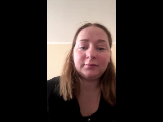 AnnaColle has light brown, straight hair, a fair complexion, and is wearing a black shirt. She has a slight smile and her tits are slightly visible.